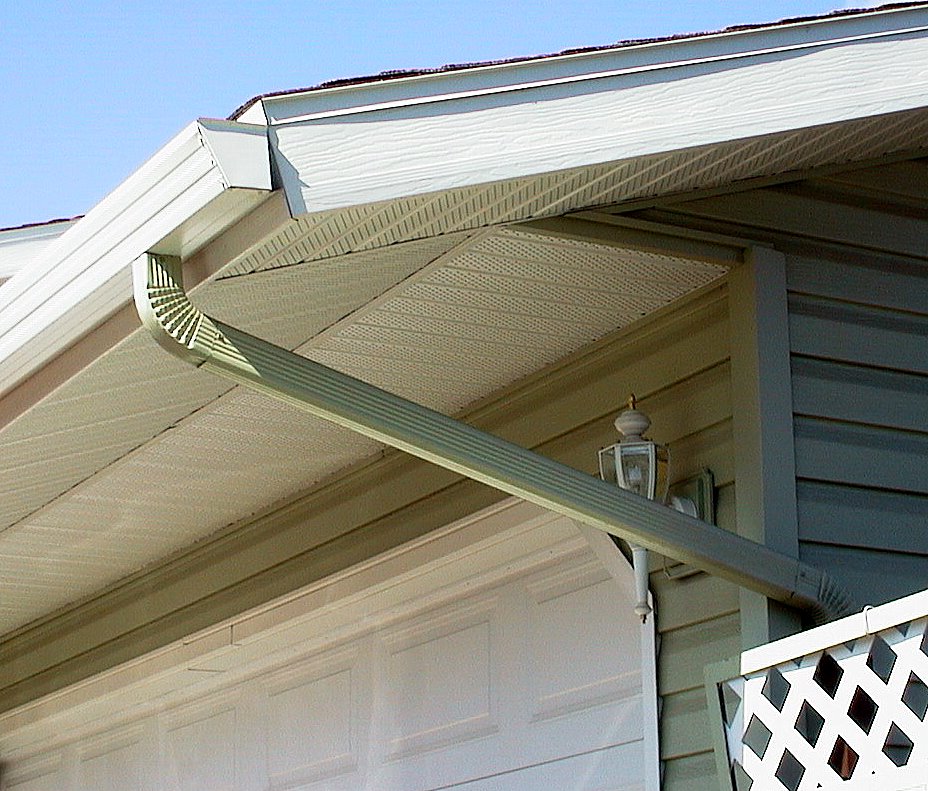 Gutters hang off the edge of a roof with a downspout going off of it and a view of soffit and fascia