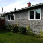 Backyard of a house with sunflowers, wall with two windows