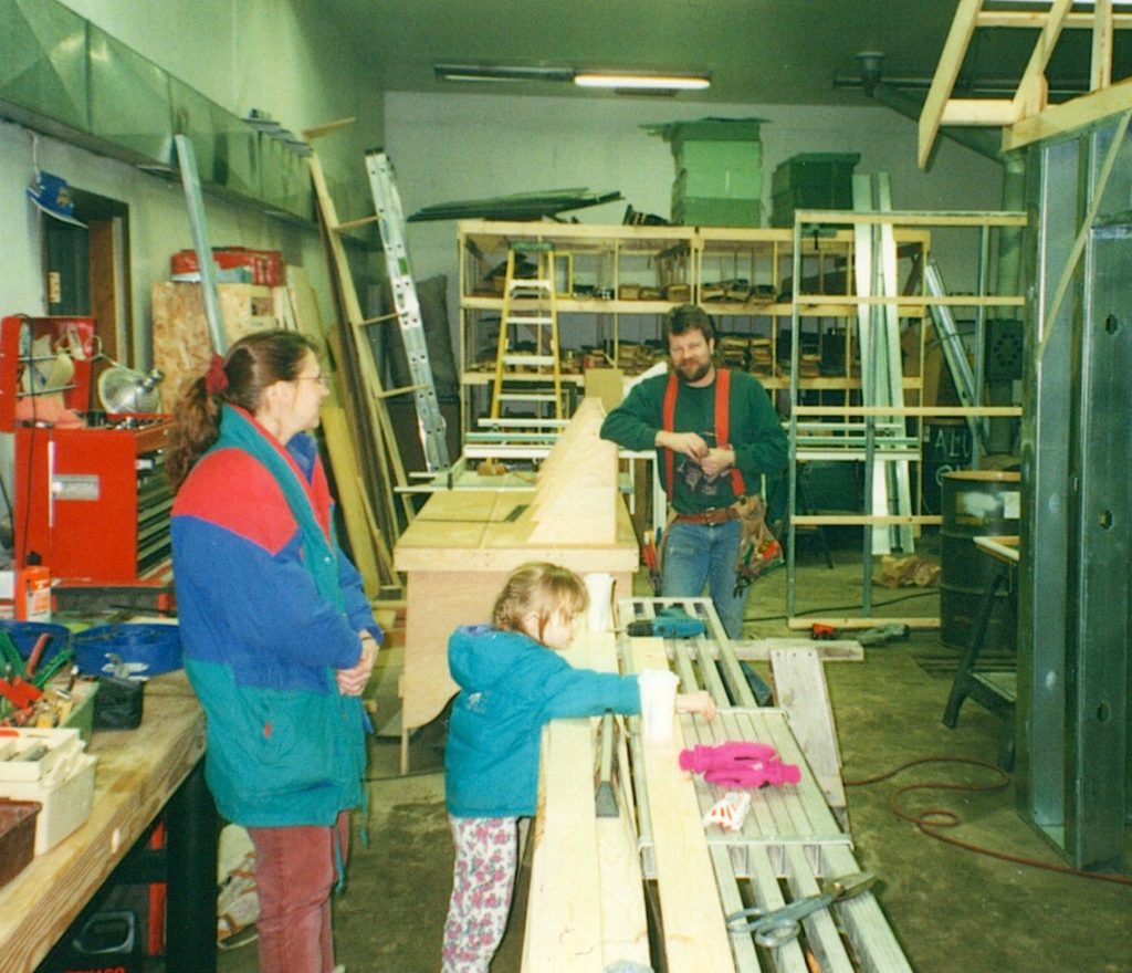 Sue and daughter watch as John works on construction project