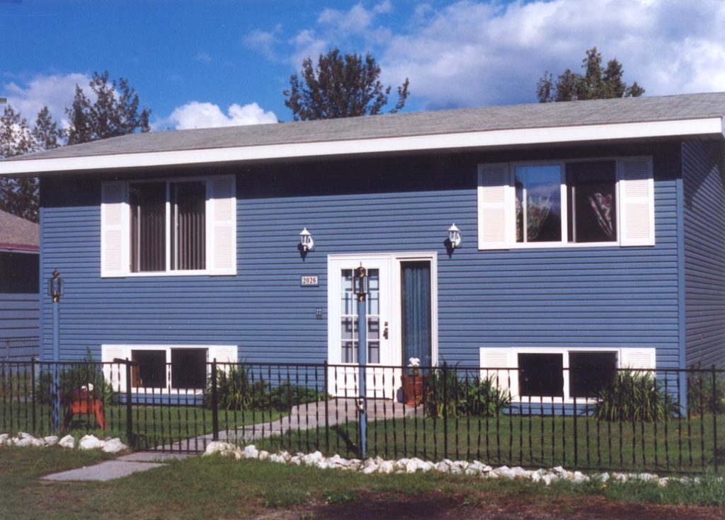 Newly completed house with blue steel siding, white doors and windows