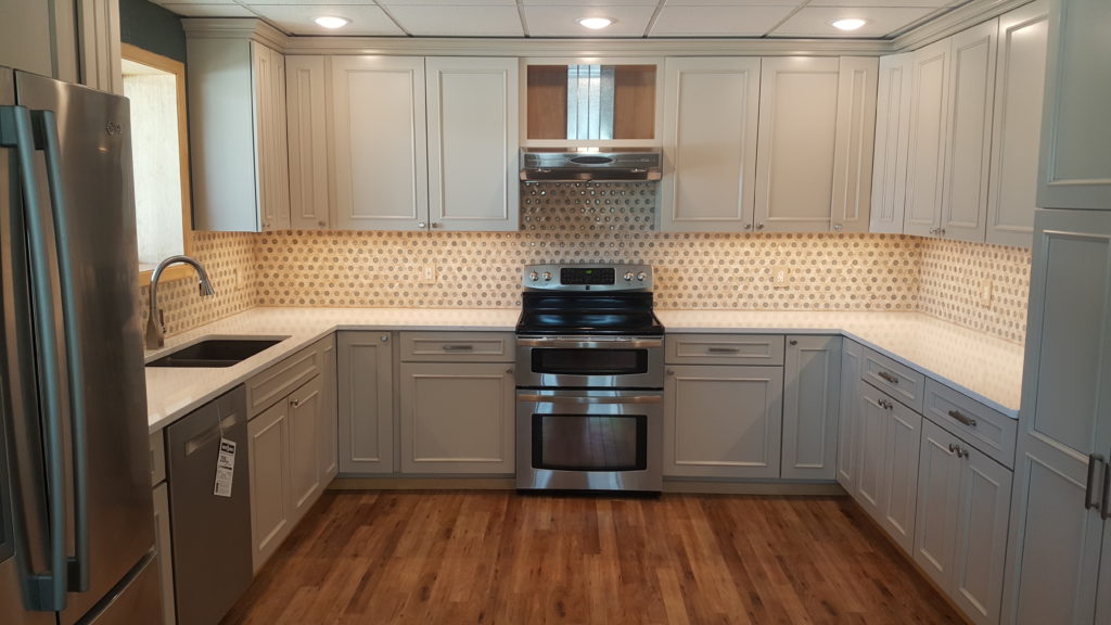 Remodeled kitchen with white cabinets, tiled backsplash, hardwood floors